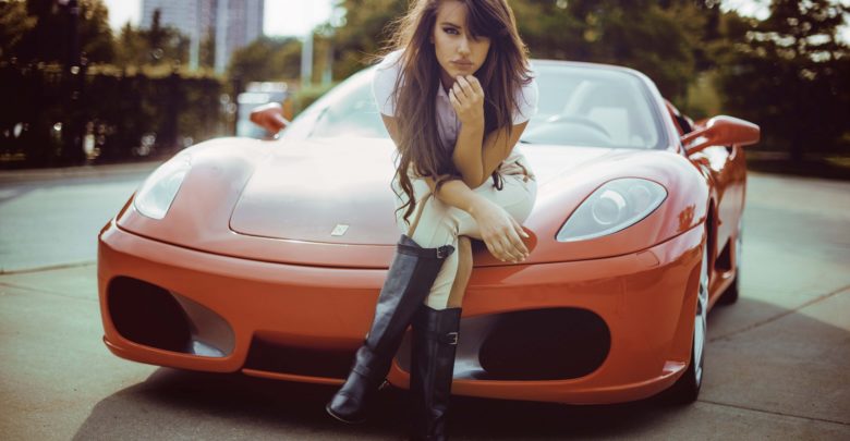 Girls Girl sitting on the hood of the orange Ferrari