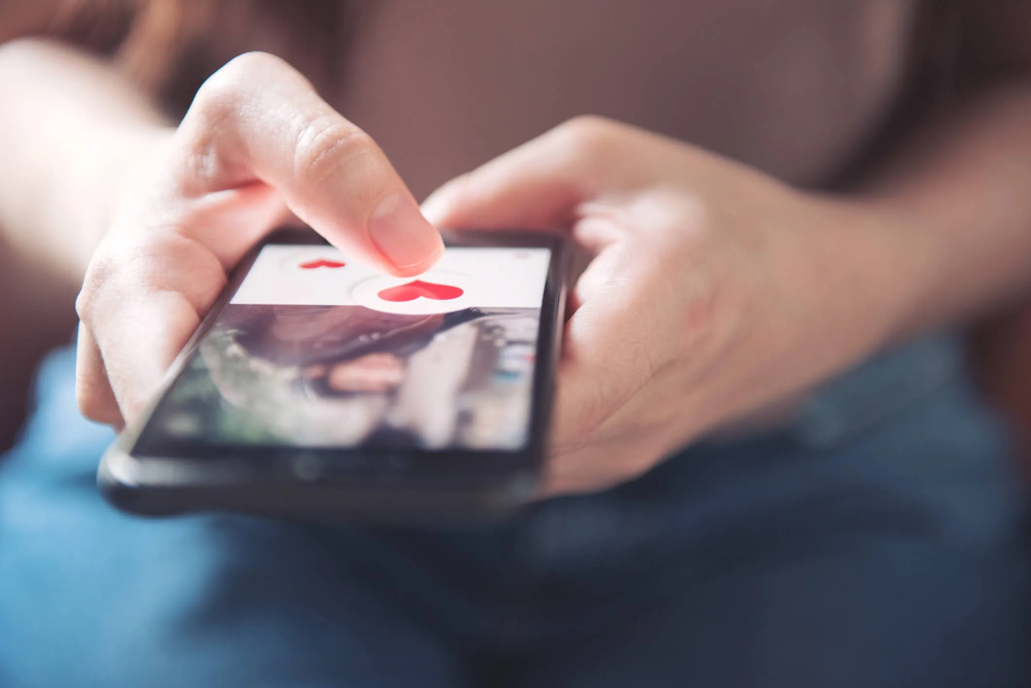 womans finger pressing on a heart on a dating app
